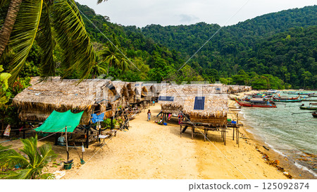 A stunning aerial view of a tropical beach village with rows of small huts along the coastline, A stunning aerial view of a tropical beach village with rows of small huts along the coastline, 125092874