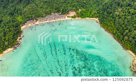 A stunning aerial view of a tropical beach village with rows of small huts along the coastline, 125092875