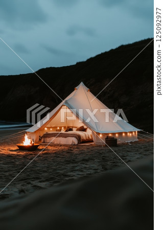 Cozy illuminated tent with campfire on a serene beachfront at dusk Cozy illuminated tent with campfire on a serene beachfront at dusk 125092977