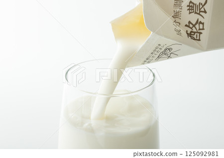 將紙盒中的牛奶倒入玻璃杯中 125092981