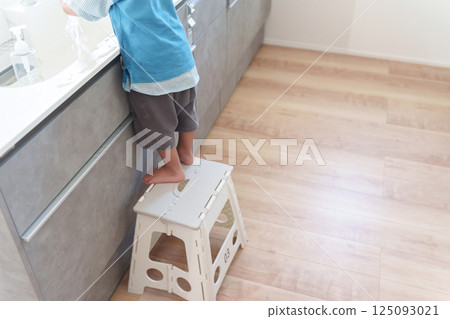 孩子站在廚房的踏腳凳上 125093021