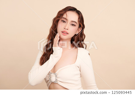 A beautiful young Asian woman with clean, fresh skin against a beige background. Skincare, facial treatment, cosmetology, beauty, and spa. An elegant portrait of an Asian woman. A beautiful young Asian woman with clean, fresh skin against a beige background. Skincare, facial treatment, cosmetology, beauty, and spa. An elegant portrait of an Asian woman. 125093445