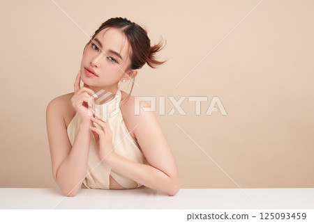 A beautiful young Asian woman with clean, fresh skin against a beige background. Skincare, facial treatment, cosmetology, beauty, and spa. An elegant portrait of an Asian woman. A beautiful young Asian woman with clean, fresh skin against a beige background. Skincare, facial treatment, cosmetology, beauty, and spa. An elegant portrait of an Asian woman. 125093459