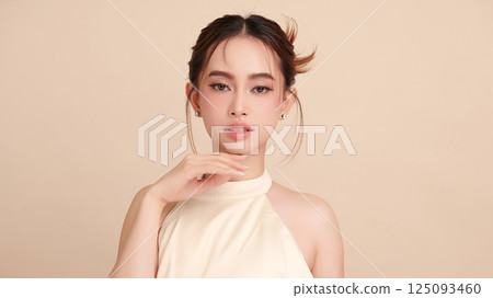 A beautiful young Asian woman with clean, fresh skin against a beige background. Skincare, facial treatment, cosmetology, beauty, and spa. An elegant portrait of an Asian woman. A beautiful young Asian woman with clean, fresh skin against a beige background. Skincare, facial treatment, cosmetology, beauty, and spa. An elegant portrait of an Asian woman. 125093460