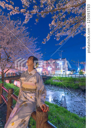 川越新河岸的櫻花盛開，漂浮著花筏，還有一位身著和服的中年婦女 125093783