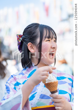 A girl walking around the town in a hakama eating soft serve ice cream on Kawagoe Taisho Roman Street A girl walking around the town in a hakama eating soft serve ice cream on Kawagoe Taisho Roman Street 125094044