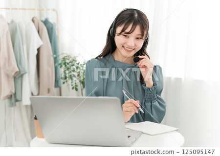 Asian woman listening to music (audiobook) with headphones at office/home 125095147