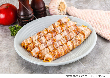 Raw sausages wrapped in bacon 125095676