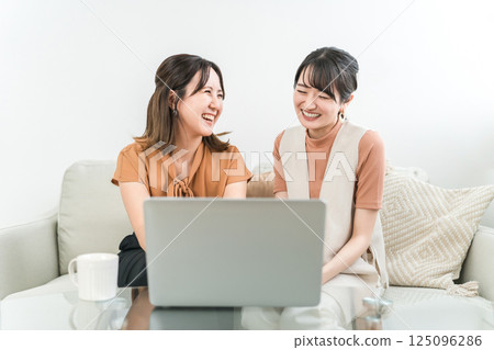 Women watching videos, movies, and live streams on their computers 125096286