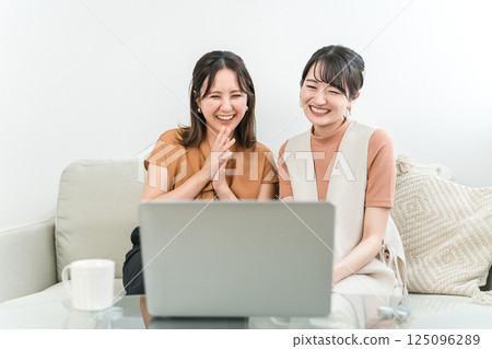 Women watching videos, movies, and live streams on their computers 125096289