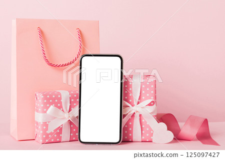 mobile phone with blank screen on colored background with hearts, calendar and gift box, valentine day concept perspertive view flat lay mobile phone with blank screen on colored background with hearts, calendar and gift box, valentine day concept perspertive view flat lay 125097427