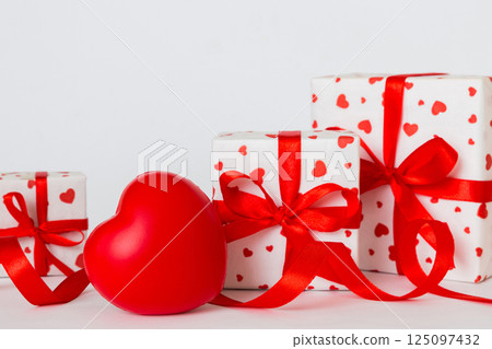 gift box with red bow and red heart on colored background. Perspective view. Flat lay gift box with red bow and red heart on colored background. Perspective view. Flat lay 125097432