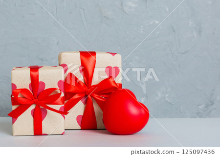 gift box with red bow and red heart on colored background. Perspective view. Flat lay gift box with red bow and red heart on colored background. Perspective view. Flat lay 125097436