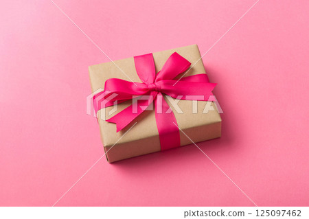 Wrapped christmas or other holiday handmade present in craft paper with colored ribbon. Present box, decoration of gift on table, top view with copy space 125097462