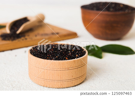 quinoa seeds in bowl and spoon on colored background. Healthy kinwa in small bowl. Healthy superfood quinoa seeds in bowl and spoon on colored background. Healthy kinwa in small bowl. Healthy superfood 125097463