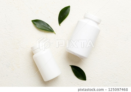 supplement pills with medicine bottle health care and medical top view. Vitamin tablets. Top view mockup bottle for pills and vitamins with green leaves, natural organic bio supplement, copy space 125097468