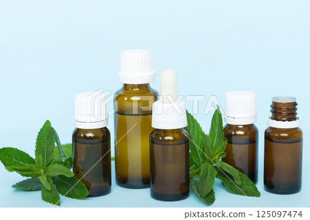Natural Mint Essential Oil in a Glass Bottle. organic cosmetics with herbal extracts of mint on colored background Natural Mint Essential Oil in a Glass Bottle. organic cosmetics with herbal extracts of mint on colored background 125097474