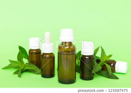 Natural Mint Essential Oil in a Glass Bottle. organic cosmetics with herbal extracts of mint on colored background 125097475
