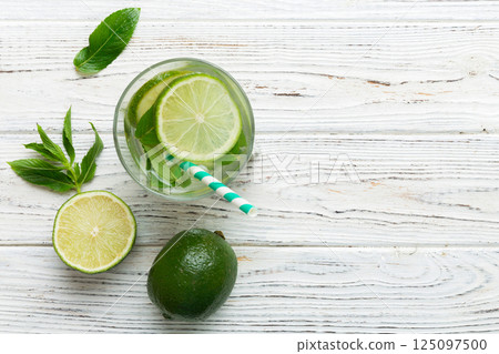 Caipirinha, Mojito cocktail, vodka or soda drink with lime, mint and straw on table background. Refreshing beverage with mint and lime in glass top view flat lay Caipirinha, Mojito cocktail, vodka or soda drink with lime, mint and straw on table background. Refreshing beverage with mint and lime in glass top view flat lay 125097500