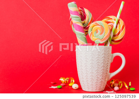Colorful candies in cup on table on light background background. Large swirled lollipops. Creative concept of a jar full of delicious sweets from the candy store 125097539
