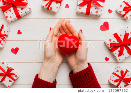 Close up on female hands holding a heart in a colored background for valentine day, birthday, mother's day. Flat lay top view Close up on female hands holding a heart in a colored background for valentine day, birthday, mother's day. Flat lay top view 125097562