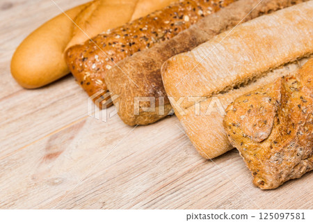 Homemade natural breads. Different kinds of fresh bread as background, perspective view with copy space Homemade natural breads. Different kinds of fresh bread as background, perspective view with copy space 125097581