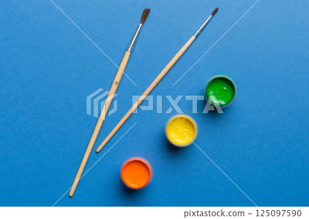 art palette with paint and brushes, close up. Top view with empty space. workplace for creativity. home teaching concept drawing 125097590