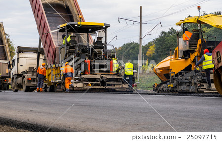 Two Asphalt Paver Machine laying fresh asphalt on road construction site. 125097715