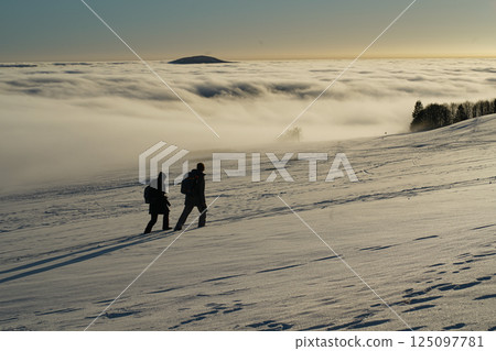 The concept of relaxing in the mountains in winter in the snow on skis, snowboards or sleds, walking under the setting sun at sunset on the Wasserkuppe mountain in Hesse Germany The concept of relaxing in the mountains in winter in the snow on skis, snowboards or sleds, walking under the setting sun at sunset on the Wasserkuppe mountain in Hesse Germany 125097781