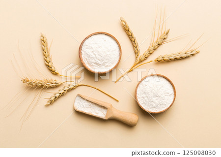 Flat lay of Wheat flour in wooden bowl with wheat spikelets on colored background. world wheat crisis 125098030