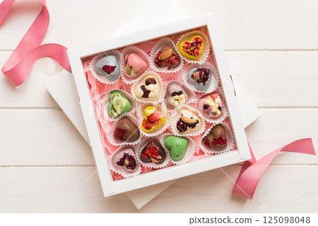 Holiday composition: sweet candy, with gift boxes with bow and chocolate hearts, photo template, background. Top View with copy space on colored background Holiday composition: sweet candy, with gift boxes with bow and chocolate hearts, photo template, background. Top View with copy space on colored background 125098048