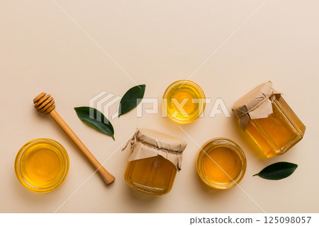 Honey jar with wooden honey dipper on white background top view with copy space. Delicious honey bottle Honey jar with wooden honey dipper on white background top view with copy space. Delicious honey bottle 125098057