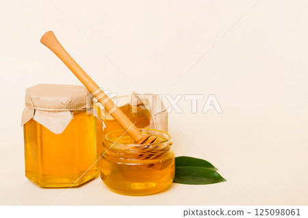 Honey in jar with leaves and honey dipper on colored background top view with copy text Honey in jar with leaves and honey dipper on colored background top view with copy text 125098061
