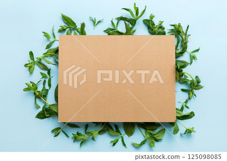 Wreath frame made of empty paper blank with space for text and mint leaves on colored background. . Mint Pattern. Flat lay. Top view Wreath frame made of empty paper blank with space for text and mint leaves on colored background. . Mint Pattern. Flat lay. Top view 125098085