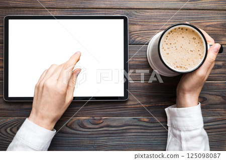 Close up image woman hands holding digital tablet with blank copy space screen for your text message or promotional content om table with cup of coffee. hands of a woman holding blank tablet device Close up image woman hands holding digital tablet with blank copy space screen for your text message or promotional content om table with cup of coffee. hands of a woman holding blank tablet device 125098087