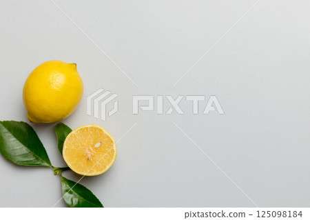Many fresh ripe lemons with green leaves on colored background, top view, space for text Many fresh ripe lemons with green leaves on colored background, top view, space for text 125098184