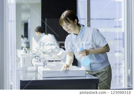 A young female cleaner wipes the sink in an office building bathroom. Photo courtesy of Tokyo Electronics College, Denpa Gakuen Corporation 125098318
