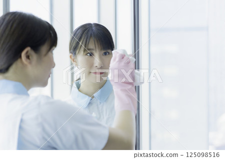 一名年輕的女清潔工正在擦拭辦公大樓衛浴的鏡子。照片提供：東京電子專門學校、電波學園 125098516