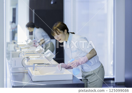 A young female cleaner wipes the sink in an office building bathroom. Photo courtesy of Tokyo Electronics College, Denpa Gakuen Corporation 125099086