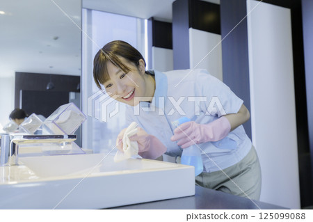 A young female cleaner wipes the sink in an office building bathroom. Photo courtesy of Tokyo Electronics College, Denpa Gakuen Corporation A young female cleaner wipes the sink in an office building bathroom. Photo courtesy of Tokyo Electronics College, Denpa Gakuen Corporation 125099088