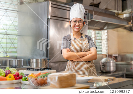 Smiling Female Chef in Kitchen with Fresh Vegetables on Counter 125099287