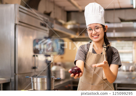 Smiling Female Chef Recording Cooking Video in Kitchen Smiling Female Chef Recording Cooking Video in Kitchen 125099295
