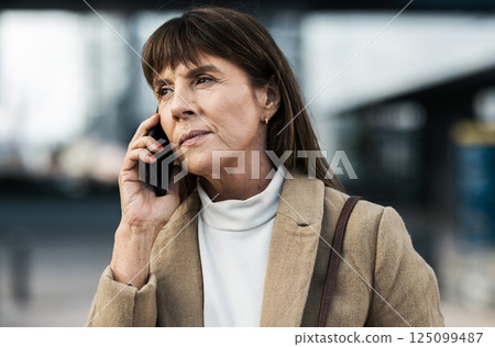 Phone call, city and serious senior woman in professional communication with legal client on mobile. Lawyer, thinking and listening to 5g smartphone conversation on urban town commute. Phone call, city and serious senior woman in professional communication with legal client on mobile. Lawyer, thinking and listening to 5g smartphone conversation on urban town commute. 125099487