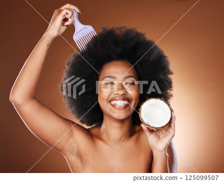 Black woman, hair care comb and coconut for beauty in studio isolated on brown background. Wellness, healthy and female model with tropical fruit and coconut oil for hair style or afro hair treatment Black woman, hair care comb and coconut for beauty in studio isolated on brown background. Wellness, healthy and female model with tropical fruit and coconut oil for hair style or afro hair treatment 125099507