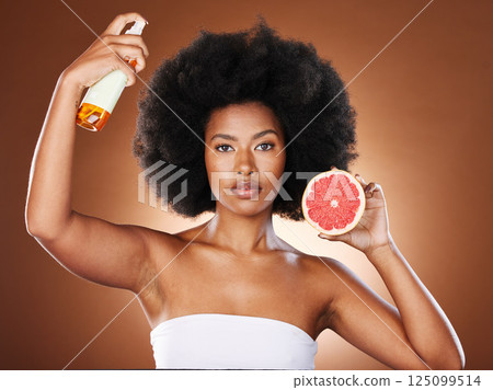 Black woman, hair care and beauty with spray, studio or wellness in portrait, health or afro with grapefruit. Woman, model and african girl with fruit, cosmetics or self care with by brown background 125099514