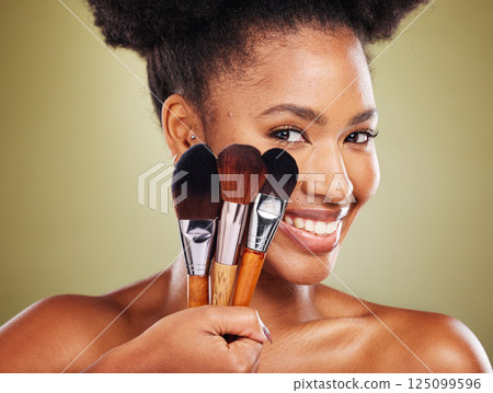 Black woman, face and brushes for makeup cosmetics, facial skincare and product on studio background. Zoom, smile portrait and happy beauty model brush, powder foundation or dermatology wellness 125099596