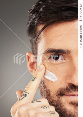 Man, face and cream for beauty, skincare and wellness with hand against a grey studio background with mockup. Male model with facial lotion on sunscreen lotion for skin health and protection from uv 125099648