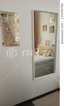 Reflection of a cozy bedroom in a wall mirror 125099786