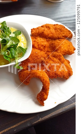 Crispy breaded schnitzel served on white plate 125099791