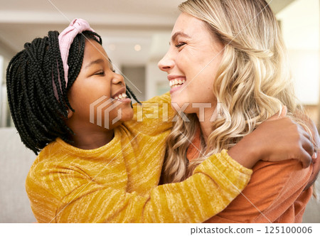 Mother, adopted and daughter bonding or hugging with love, care and affection for childhood embrace. Diverse woman and foster little girl hugging and having fun while in the family home 125100006